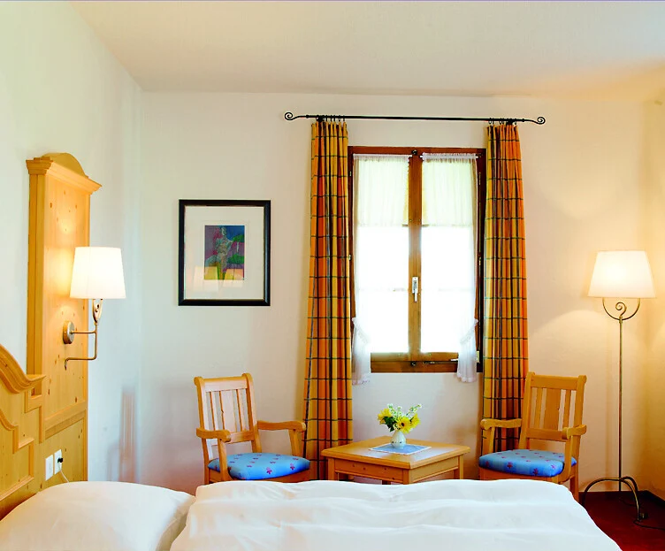 Helles Doppelzimmer mit Bett, Fenster und kleiner Sitzgruppe