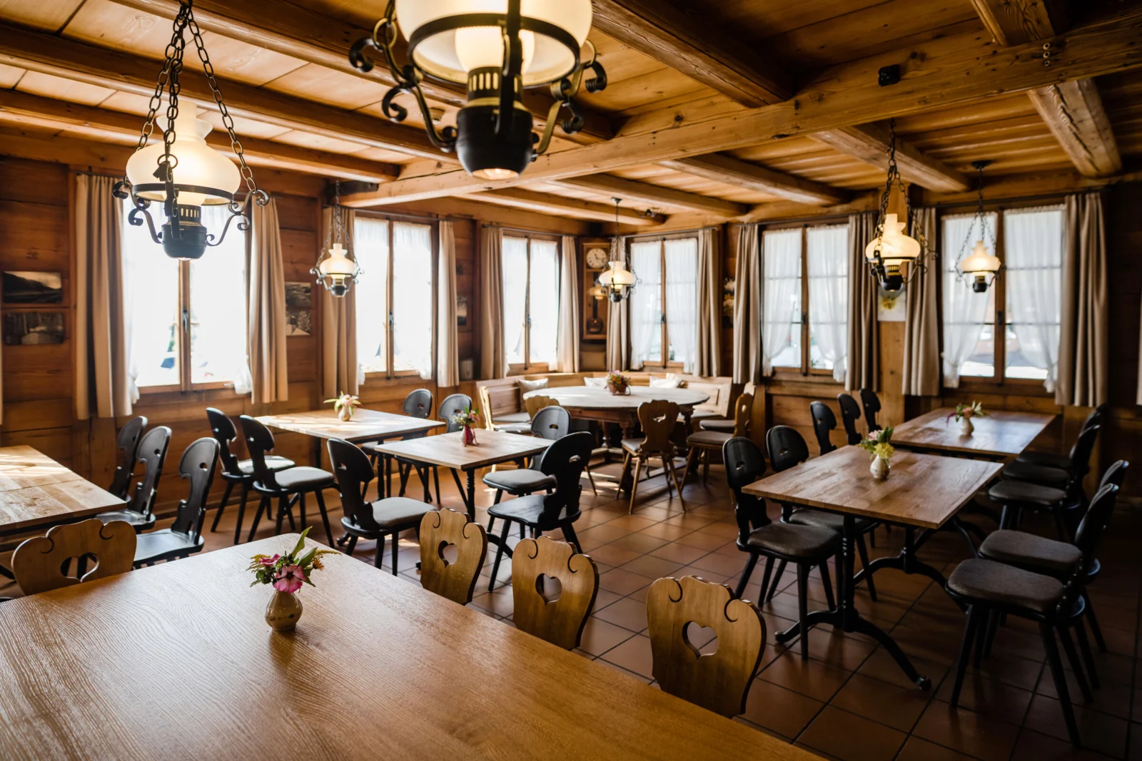 Grosse Gaststube mit Holzdecke, Kronleuchtern und gedeckten Tischen