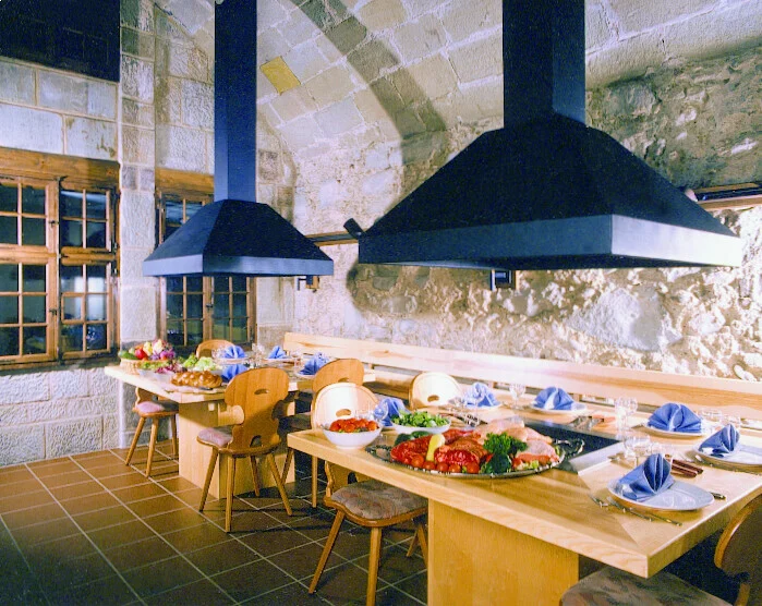 Grillbuffet mit grossen Abzugshauben und langen Holztischen