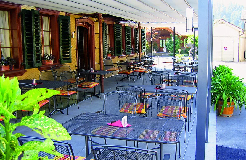 Überdachte Terrasse mit Tischen und Stühlen