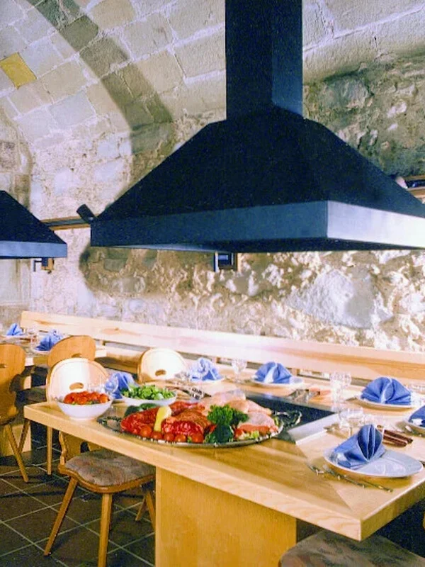 Gewölbter Bären-Keller mit gedecktem Grilltisch, Grillplatte mit Fleisch und blauen Servietten