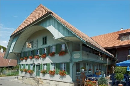 Gasthof Bären in Ranflüh, ein Emmentaler Bauernhaus mit grünen Fensterläden, Blumenschmuck und Sonnenschirm